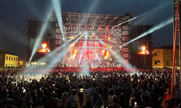 Concerto serale emozionante, luci intense e folla entusiasta in festa.